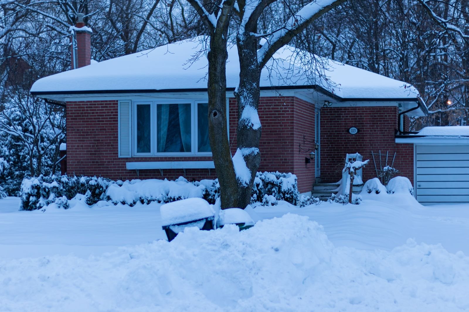 A snow-covered house on a cold blue winter evening